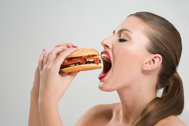 une femme qui mange un burger avec impatience