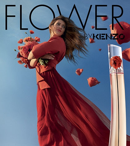 femme porte robe rouge et devant elle un parfum kenzo flower et des fleurs